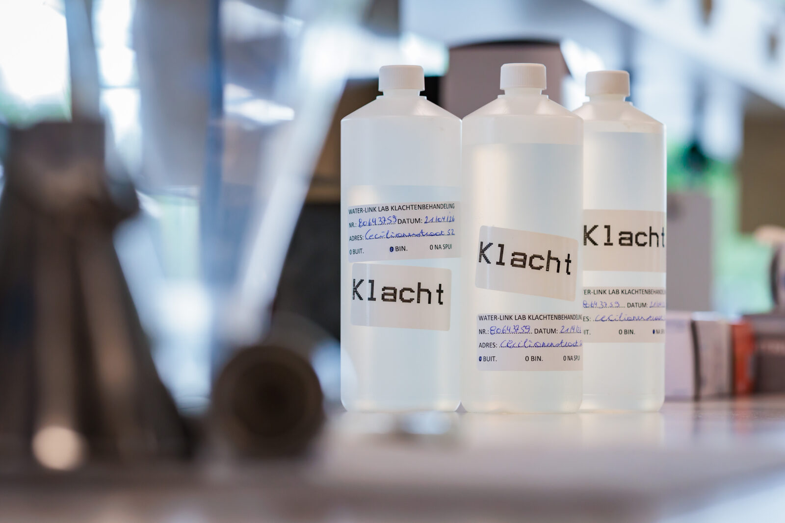 Foto 3 bussen met doorzichtig vloeistof met tekst 'klacht'